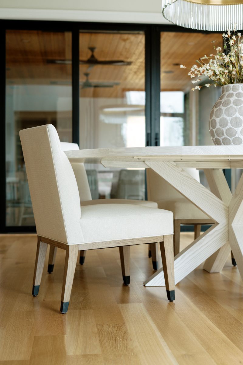 A dining room in West Des Moines with a whitewashed oak trestle table and cream linen chairs on white oak floors.