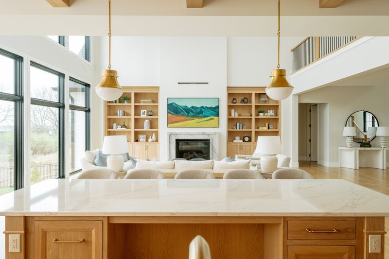 A kitchen in West Des Moines with a brass pendant over a white oak island topped in marbled quartz.