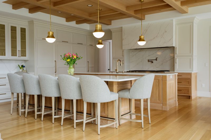 A white oak kitchen in West Des Moines with a marble slab hood over the range and brass pendants above the island.