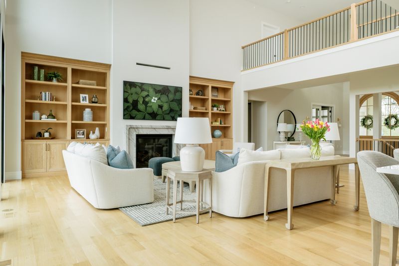 A two story living room in West Des Moines with a white oak built-in bookcase and a black metal loft railing.