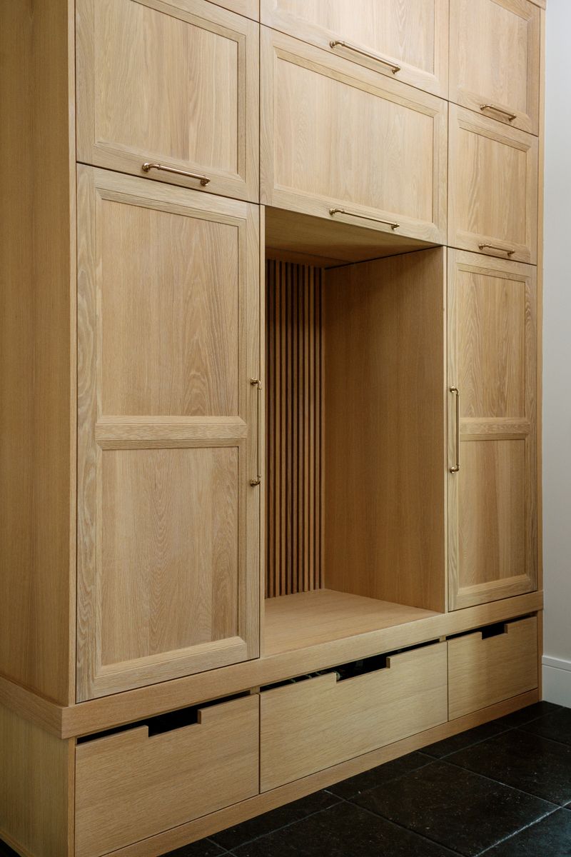 A white oak mudroom in West Des Moines with brass pulls and a slatted open locker bay.