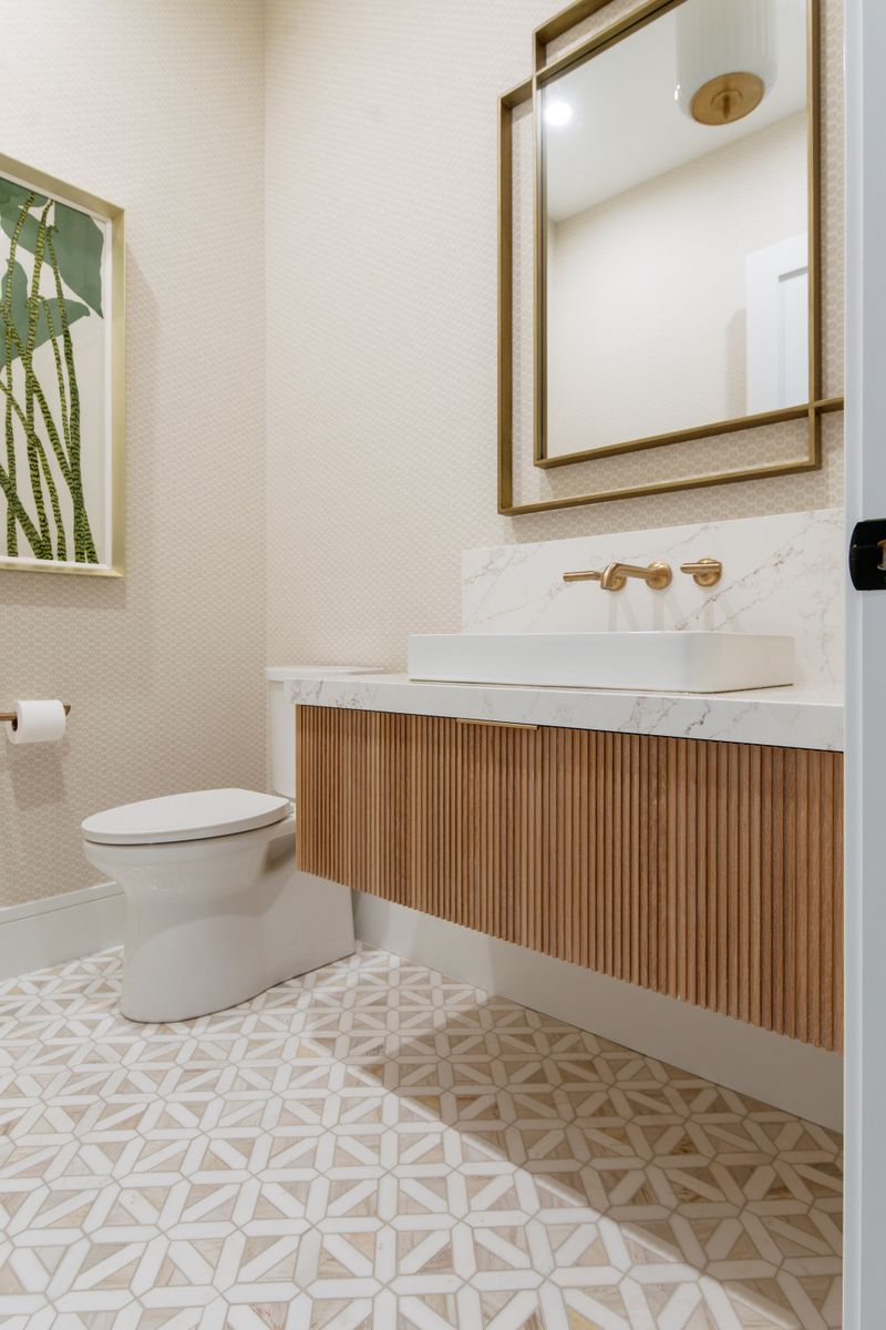 A powder room in West Des Moines with a fluted oak floating vanity under a brass wall-mount faucet.