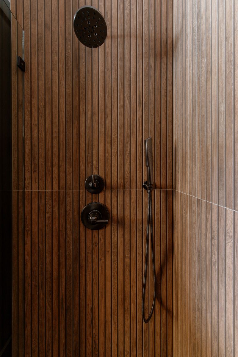A primary bath shower in West Des Moines with wood look fluted tile and matte black fixtures.