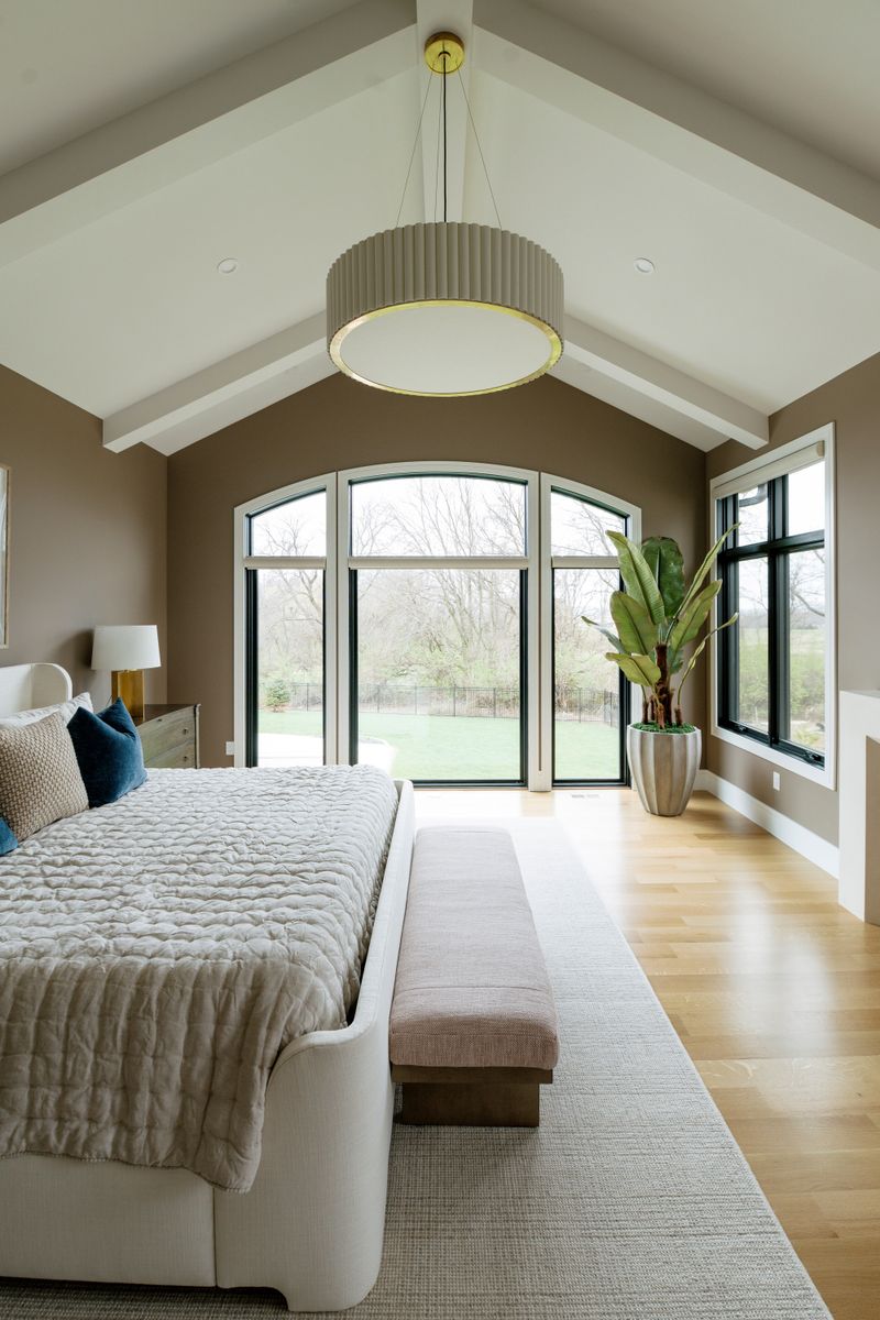 A brown primary bedroom in West Des Moines with a fluted brass pendant under a white vaulted beamed ceiling.