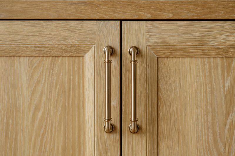 White oak cabinets in West Des Moines with long brass pulls on a pair of paneled doors.