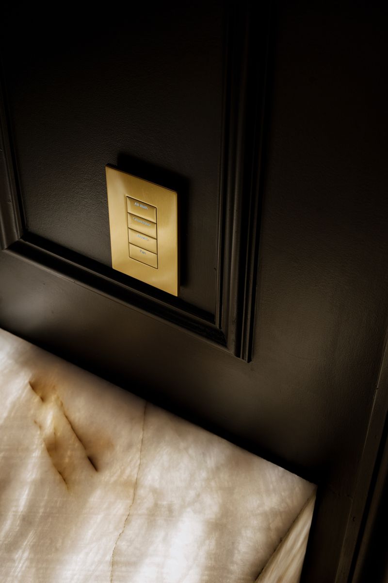 A dark green bath in Des Moines with a brass lighting keypad set above a backlit onyx counter.