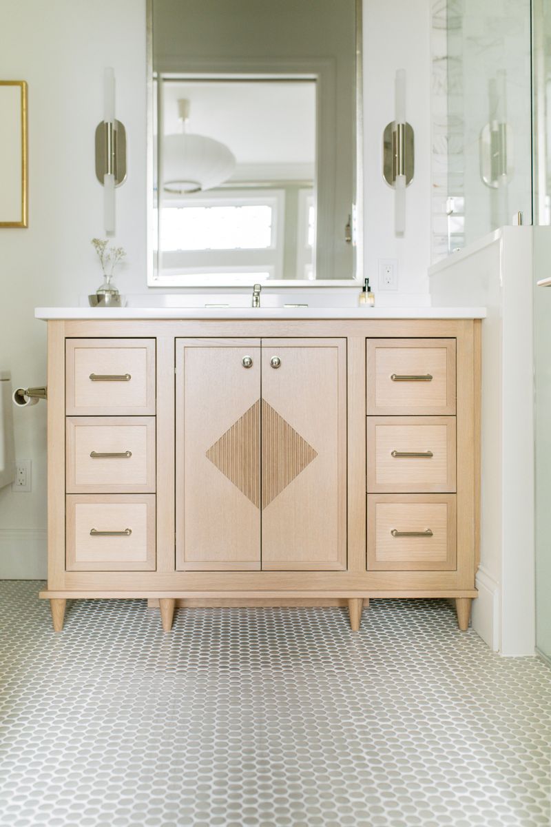 A Des Moines bath with a white oak vanity and a fluted diamond inlay, over gray penny tile floors.
