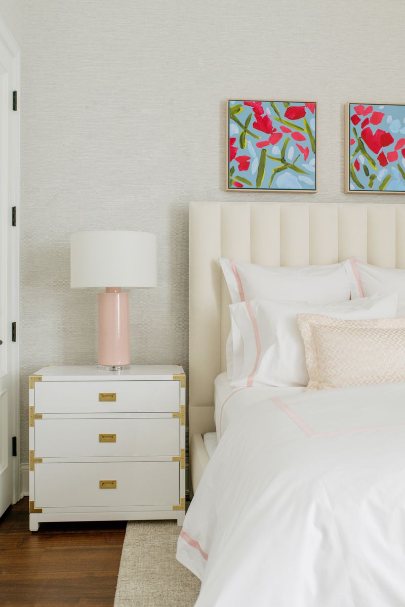 A cream bedroom in Des Moines with a white campaign nightstand in brass beside a channel tufted headboard.