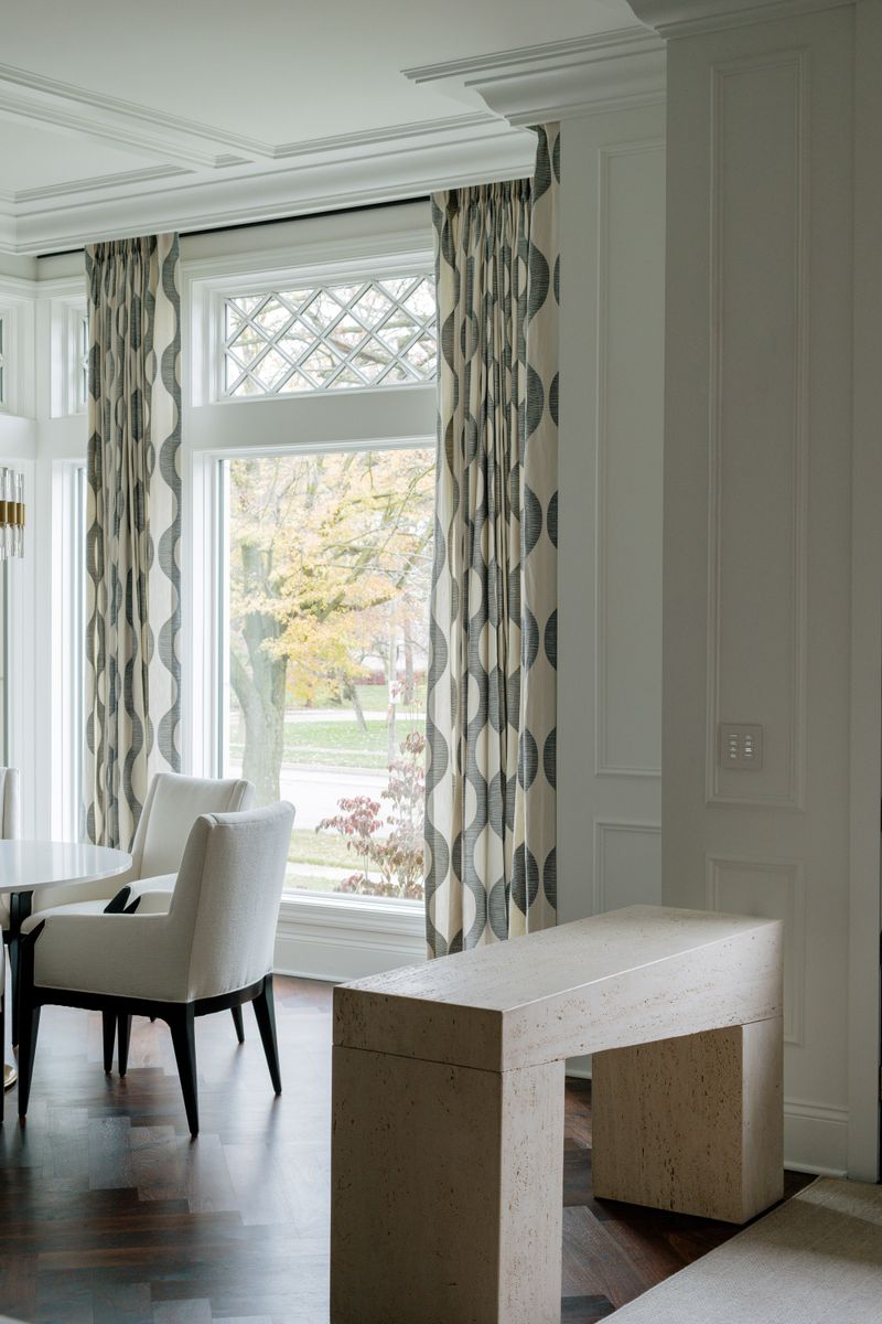 A dining room in Des Moines with a travertine console table against dark herringbone wood floors.