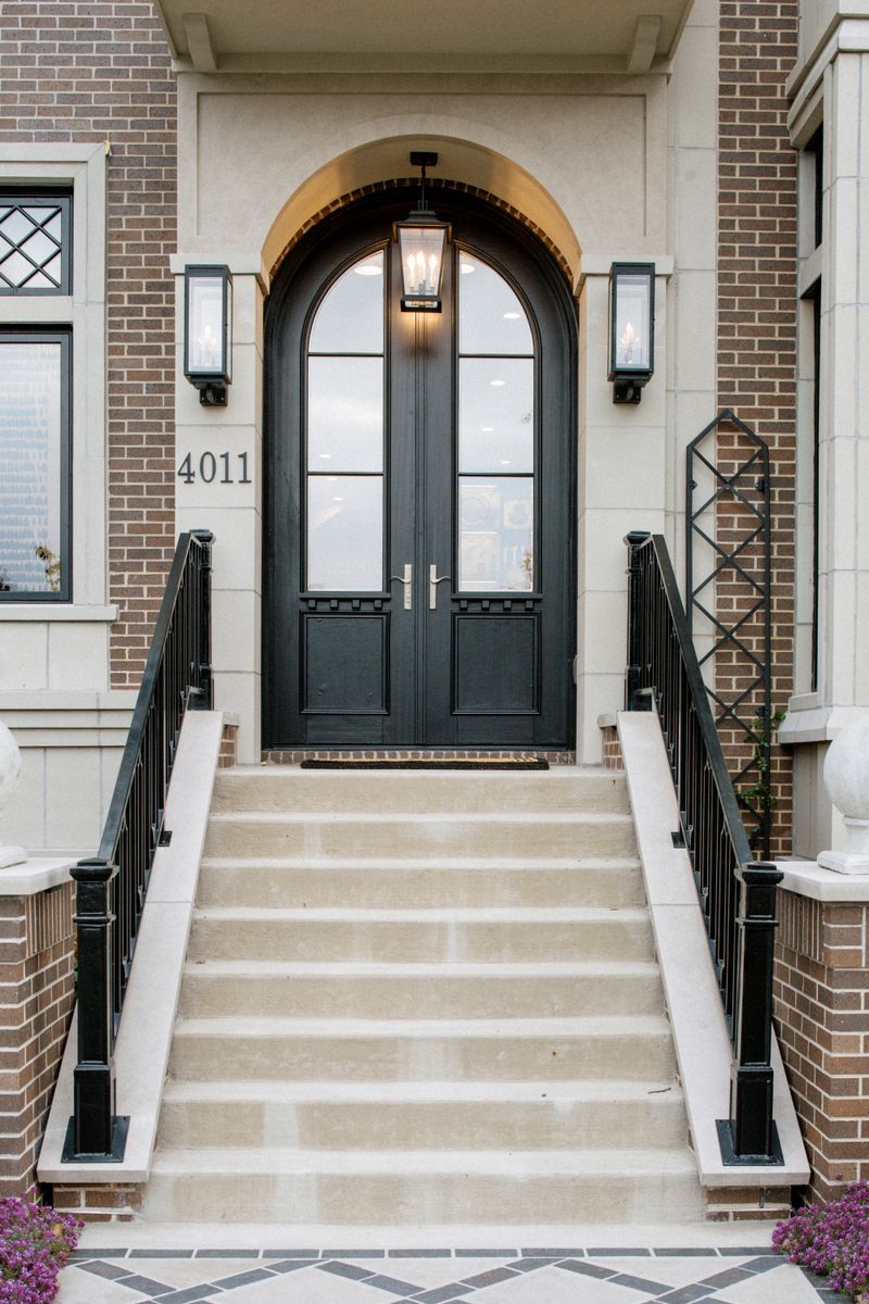 An entry in Des Moines with an arched black double door under a glass lantern, set above limestone steps.