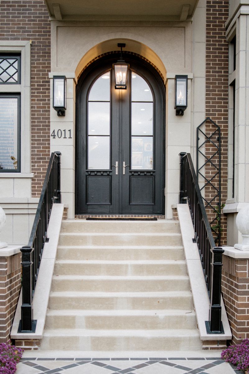 A Des Moines entry with black arched double doors under a gas lantern, framed by brick and limestone.