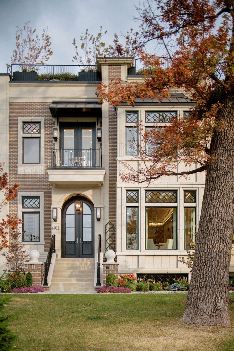 A brick and limestone home exterior in Des Moines with an arched black double door under a lantern.