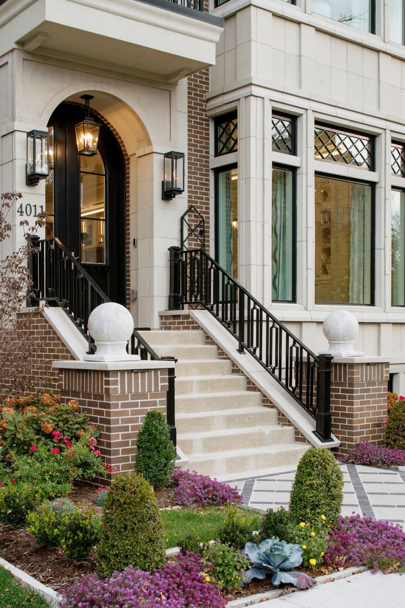 A limestone front entry in Des Moines with a black arched door under a lantern and brick steps.