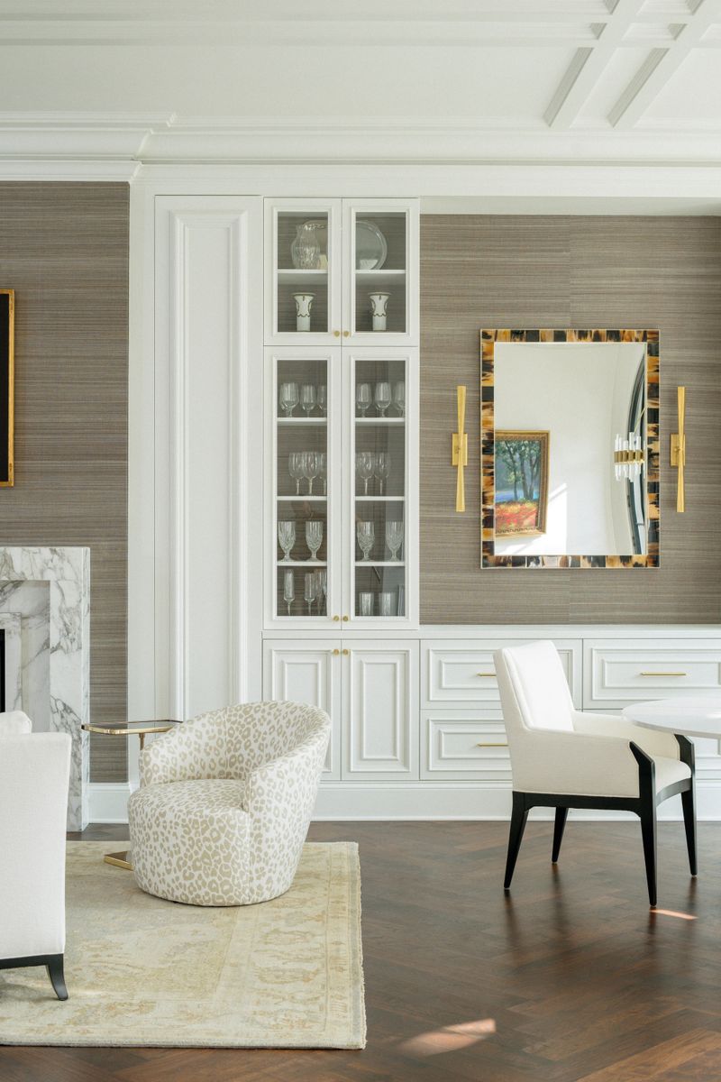 A Des Moines living room with a white glass-front built-in cabinet set against taupe grasscloth walls.