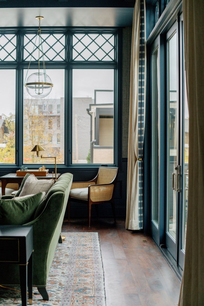 A navy trimmed living room in Des Moines with a green velvet sofa under a seeded glass globe pendant.