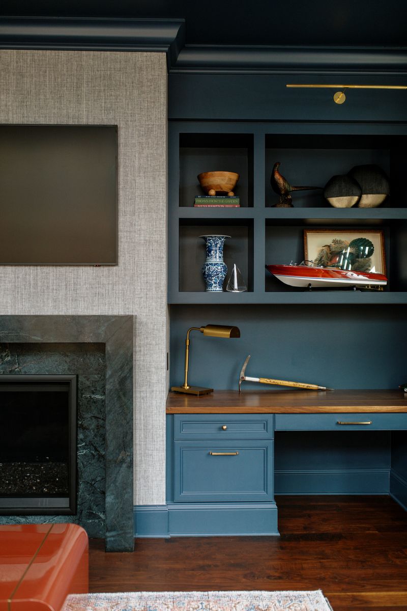 A blue home office in Des Moines with a walnut desktop built into painted blue cabinets and shelves.