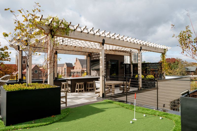 A roof terrace in Des Moines with a cedar pergola over an outdoor bar and black steel planters.