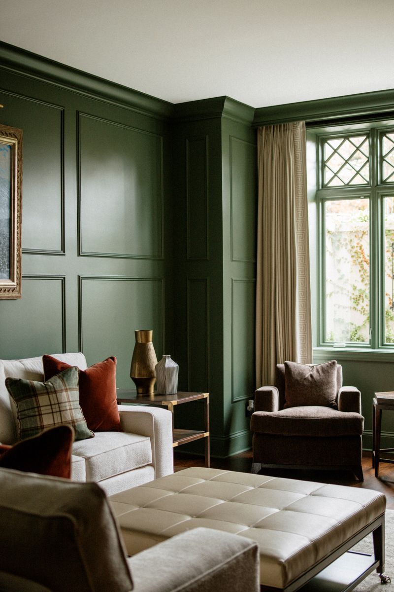 A sitting room in Des Moines with dark green paneled walls and a brown velvet armchair by the leaded window.