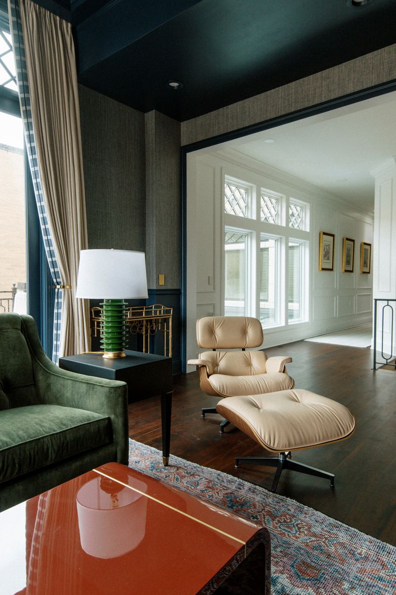 A sitting room in Des Moines with a cream leather lounge chair and ottoman under a deep teal ceiling.