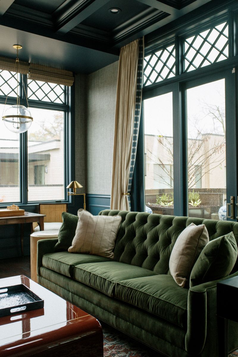 A sitting room in Des Moines with a green tufted velvet sofa under a dark navy coffered ceiling.