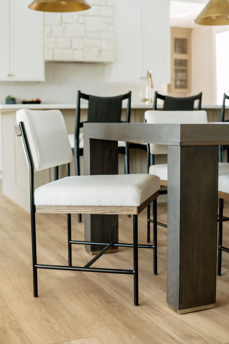 A dining room in Clive with cream boucle chairs on black metal frames around a dark oak table.