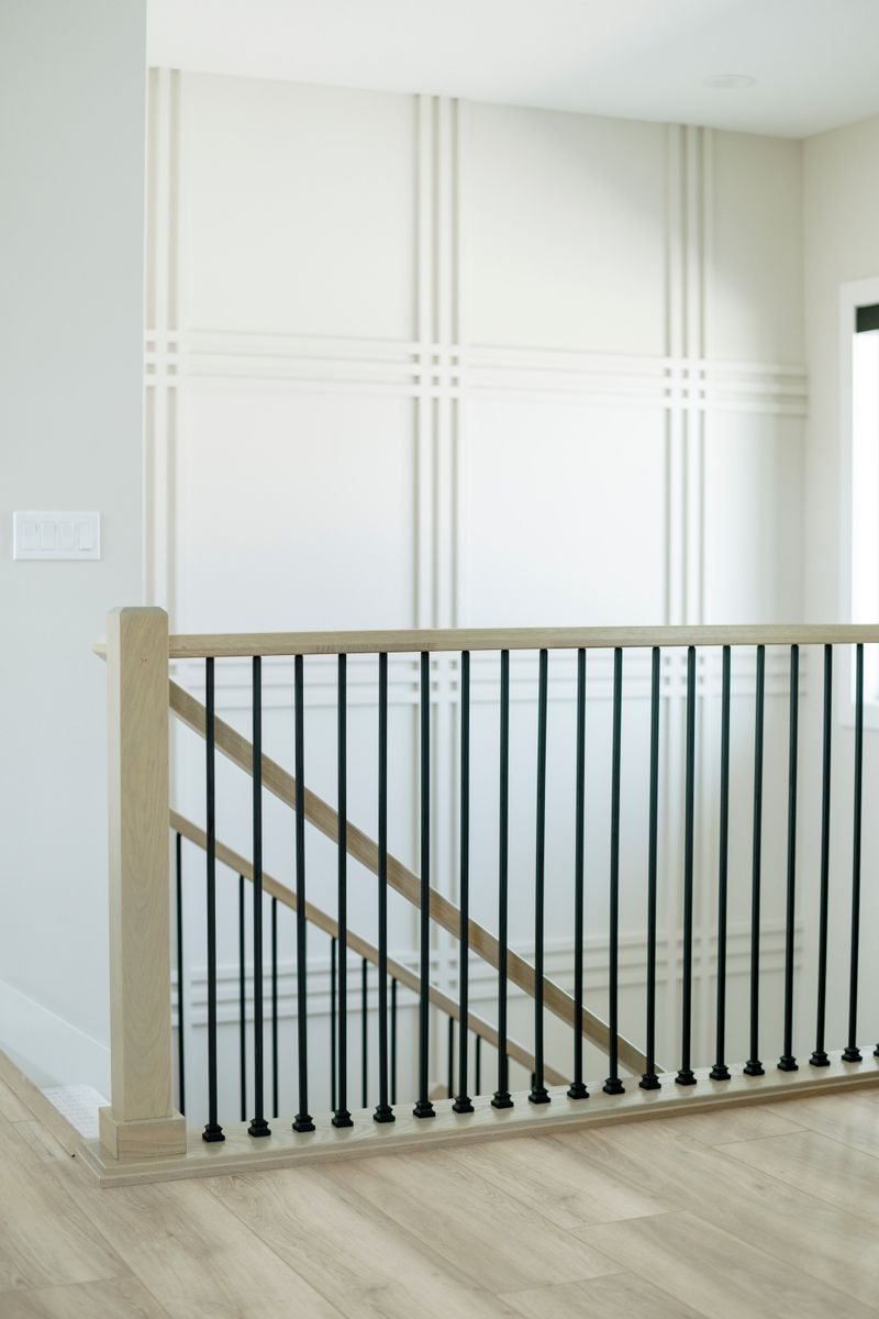 A staircase in Clive with black metal spindles under a white oak handrail, beside a cream trim wall.