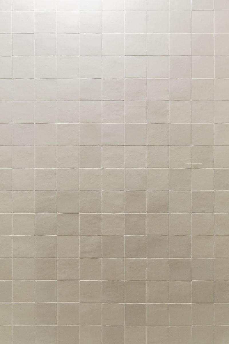 Cream square zellige tile set in a straight stacked grid on a wall in Clive, with thin white grout lines.