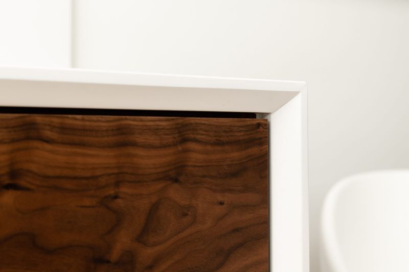 A Des Moines bath with a walnut drawer front set into a white vanity beside a freestanding tub.