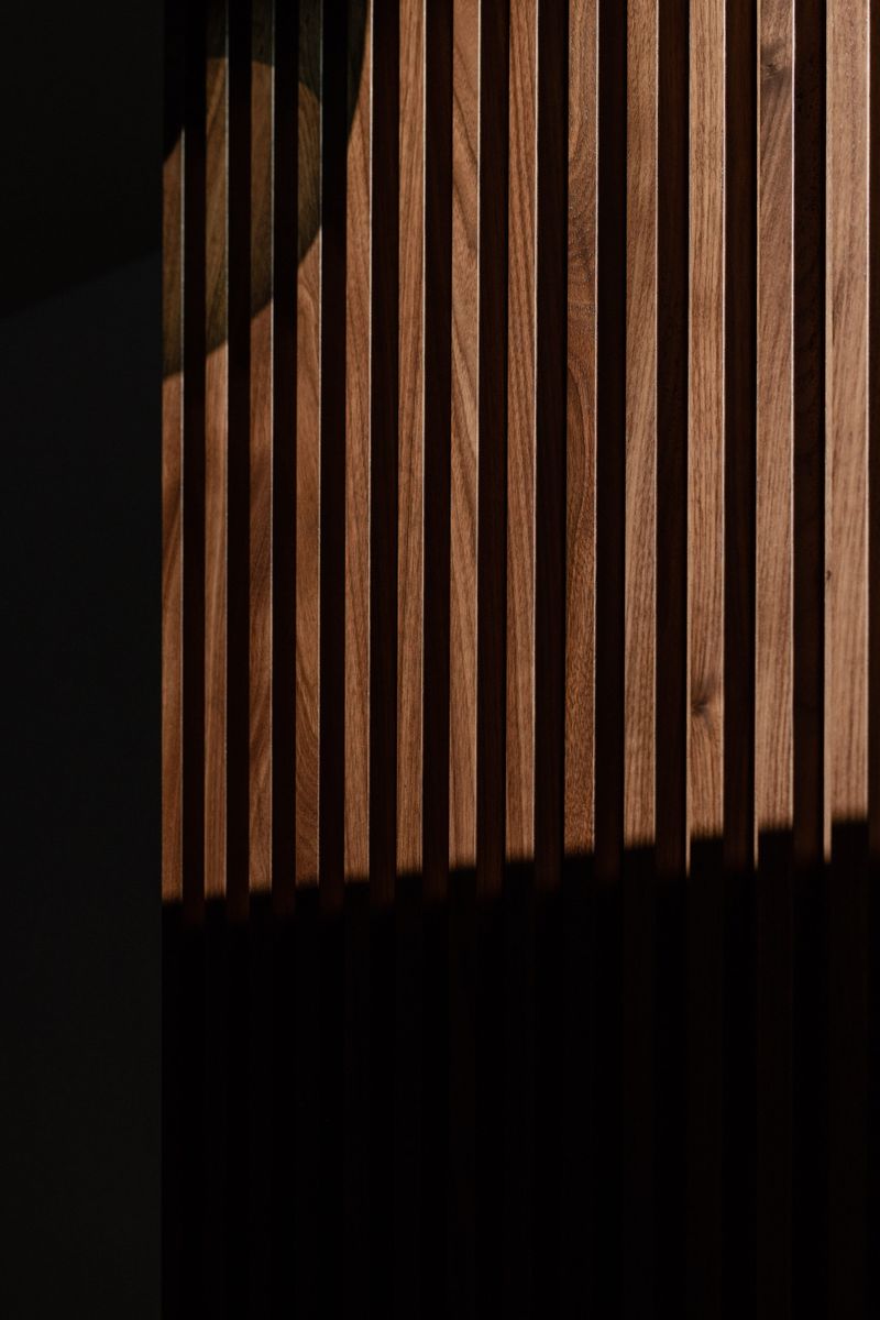 A walnut slat wall in Des Moines, with narrow vertical wood slats against a dark painted wall.