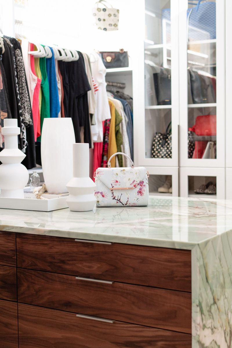 A walk in closet in Des Moines with a green marble island top over walnut drawers.