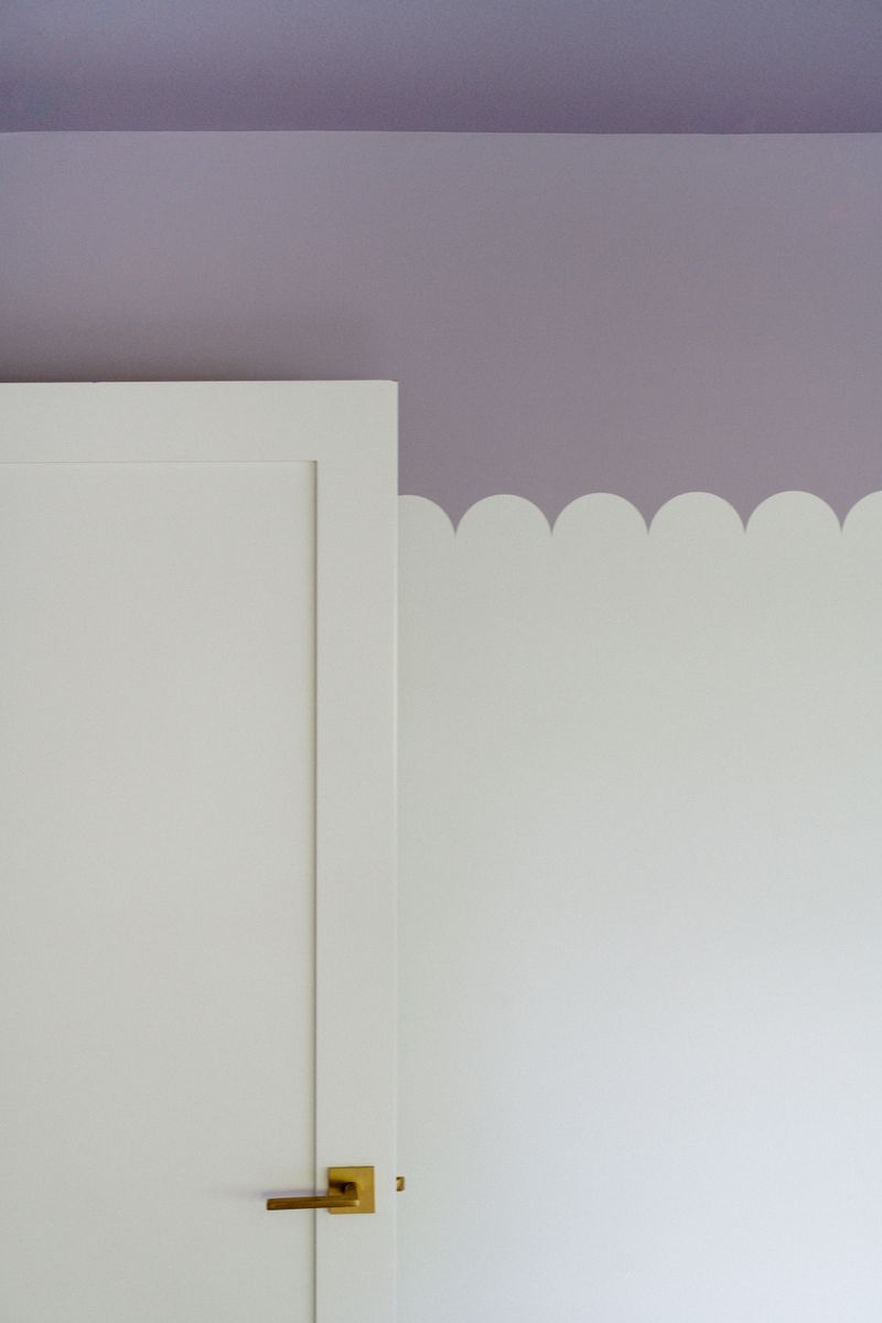 A bedroom in West Des Moines with a scalloped white wall painted against a soft lavender ceiling.