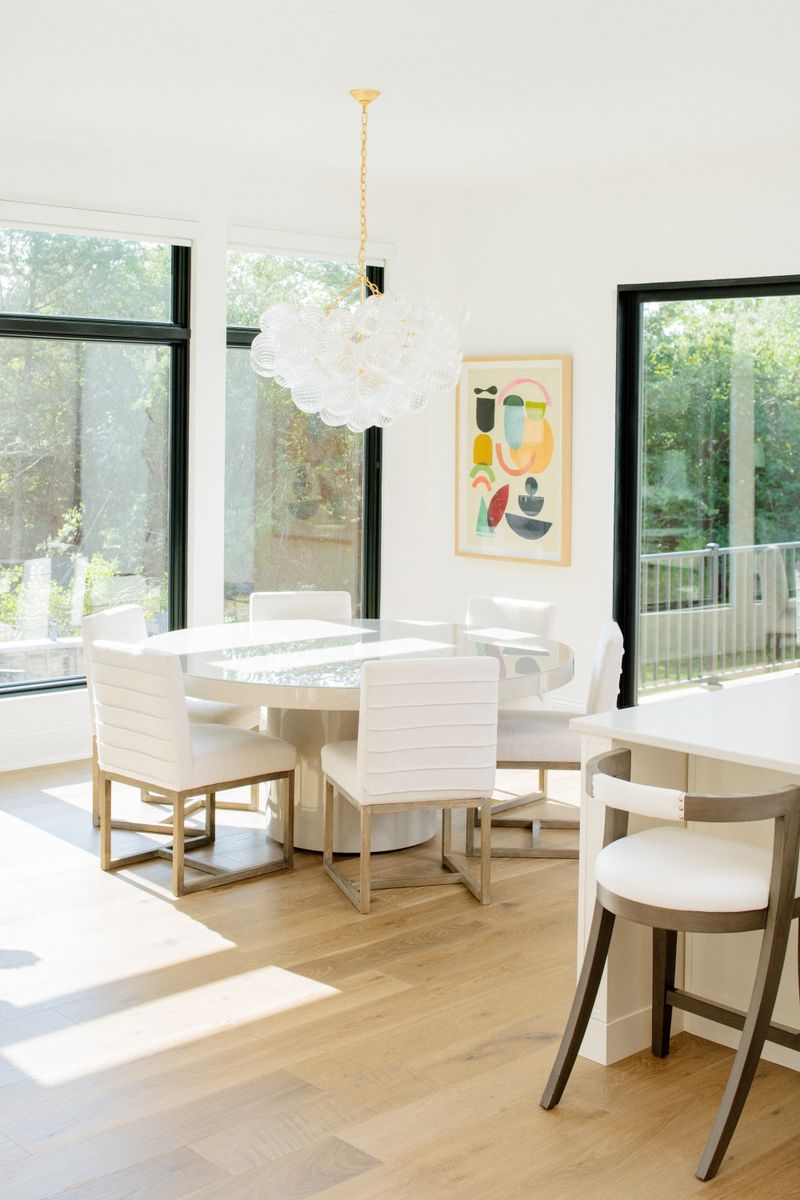 A white breakfast nook in West Des Moines with a bubble glass chandelier over a round table and white oak floors.