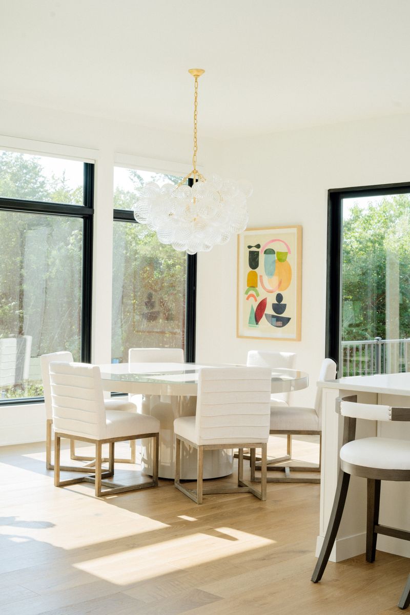A white dining area in West Des Moines with a bubble glass chandelier over a round table on white oak floors.