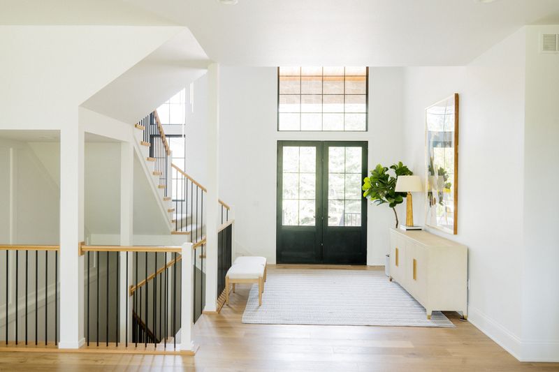 A white entry in West Des Moines with black glass double doors under a tall transom window.