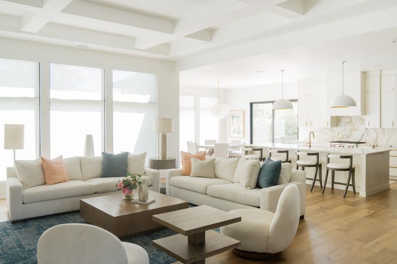 A white living room in West Des Moines with a square oak coffee table on a deep blue patterned rug.