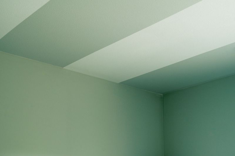 A painted room in West Des Moines with soft green walls carried up to meet a striped ceiling in the same shade.