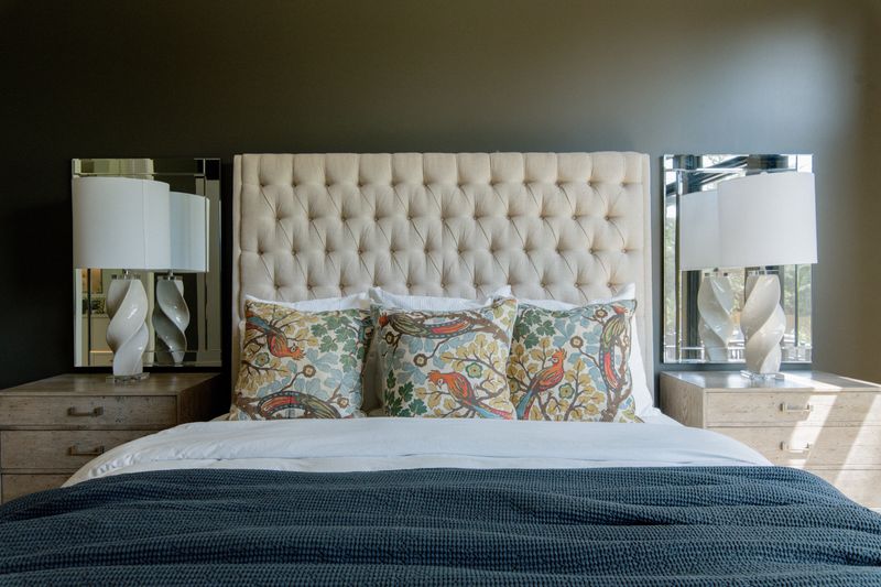 A primary bedroom in West Des Moines with a tufted linen headboard against deep olive green walls.