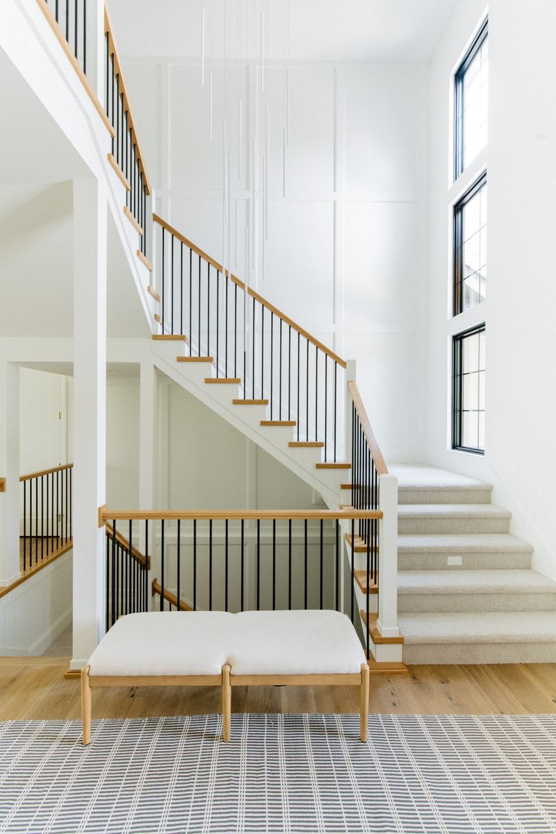 A white staircase in West Des Moines with black metal spindles under a white oak handrail.