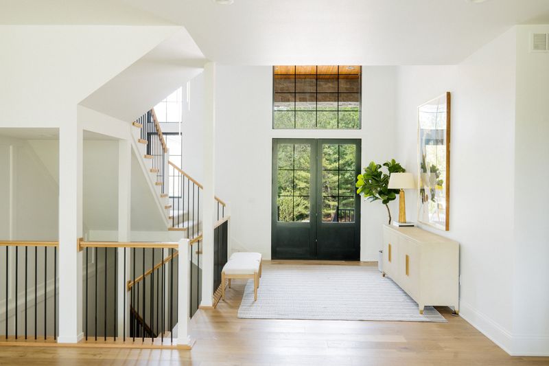A white staircase in West Des Moines with black metal spindles and a white oak handrail over light oak floors.