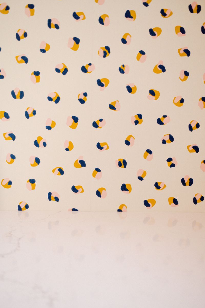 Cream wallpaper in West Des Moines with navy and gold dots above a white marble counter.