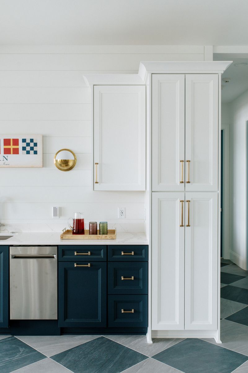 A kitchen in Panora with navy base cabinets and brass pulls under a white quartz counter.