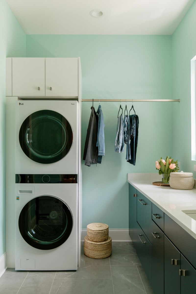 A mint green laundry room in Panora with dark teal cabinets under a white quartz counter.