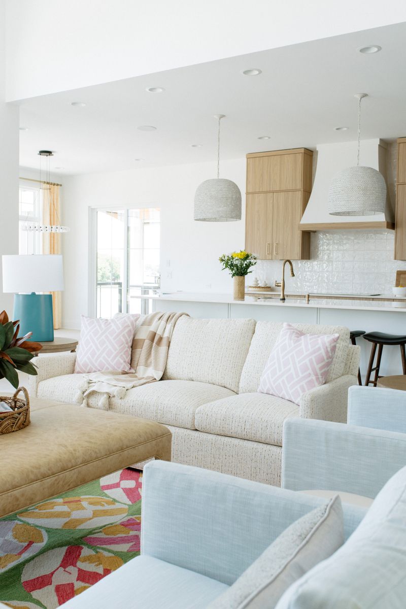 A living room in Panora with a cream tweed sofa and a tan leather ottoman on a floral wool rug.