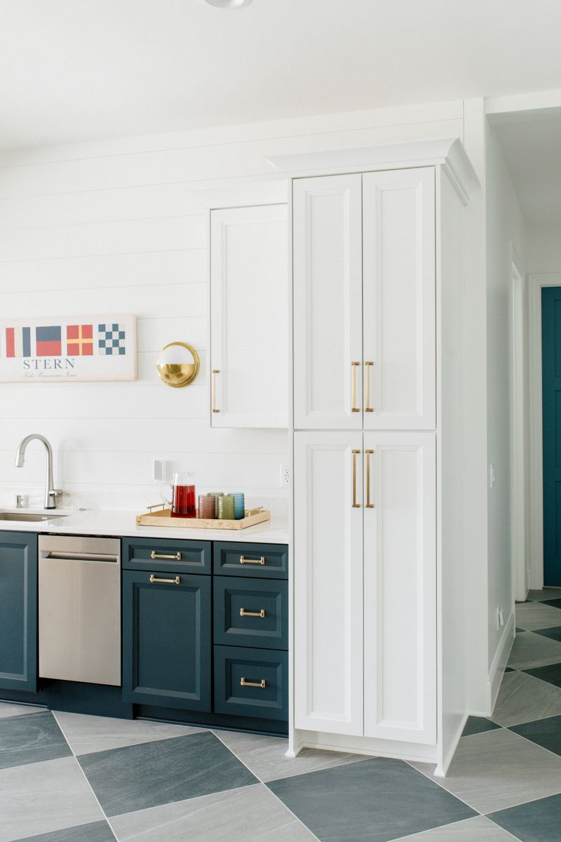 A wet bar in Panora with navy cabinets and brass pulls under a white quartz counter.